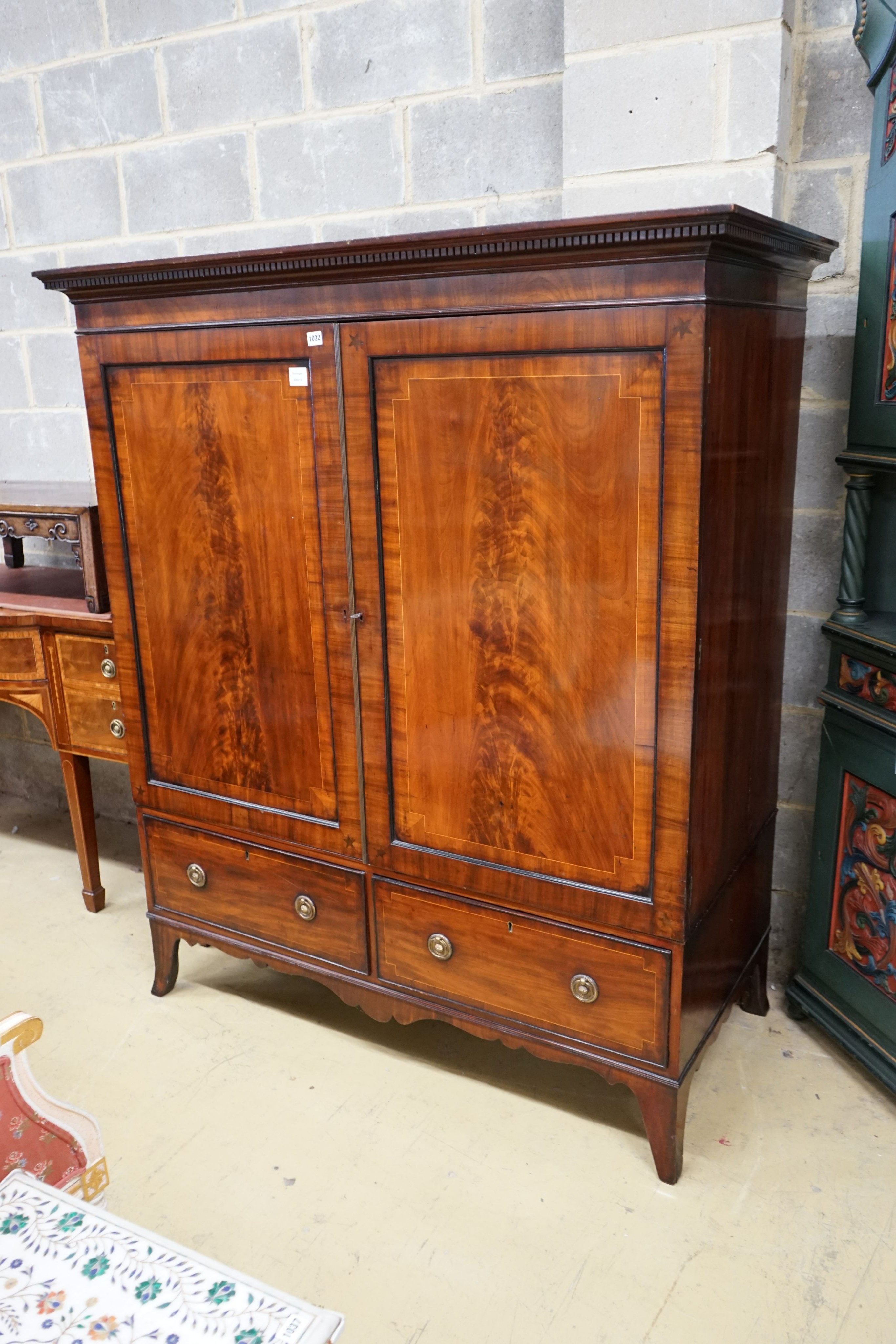 A 19th century mahogany linen press of small proportions, with panelled flamed mahogany doors centered with inlaid star motifs, width 133cm, depth 60cm, height 196cm